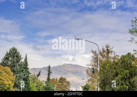 Winter Teheran Straßenansicht in Teheran International Exhibition Centre mit Schneebedeckte Alborz Berge gegen bewölkten Himmel auf Hintergrund Stockfoto