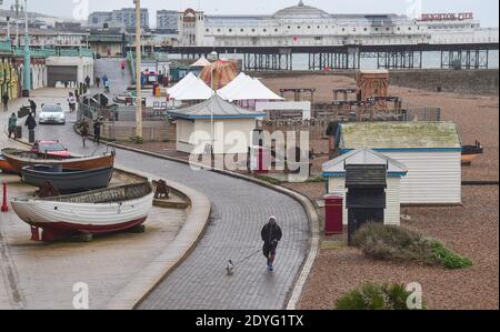 Brighton UK 26. Dezember 2020 - EIN Boxing Day Hundespaziergänger an der Küste von Brighton während des trüben Nieselwetters entlang der Südküste, als sich Storm Bella Großbritannien nähert : Credit Simon Dack / Alamy Live News Stockfoto