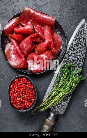 Getrocknete gesalzene bresaola Rindfleisch Fleisch in dünne Scheiben geschnitten. Schwarzer Hintergrund. Draufsicht Stockfoto