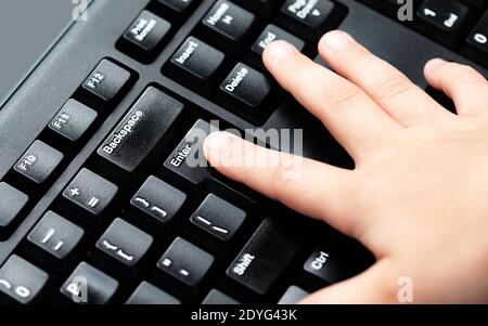 Kind, kleiner Finger drücken ENTER-Taste auf Desktop-pc-Tastatur. Kinder Finger drücken ENTER-Taste auf Computer-Tastatur Nahaufnahme Kinder Sicherheit Stockfoto