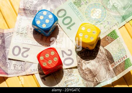 Drei bunte Spielwürfel, die sechs auf polnischen Zloty-Scheinen legen. Polnische złoty Bargeld, Banknoten und viele Würfel, die 6 zeigen. Spielen und gewinnen Stockfoto