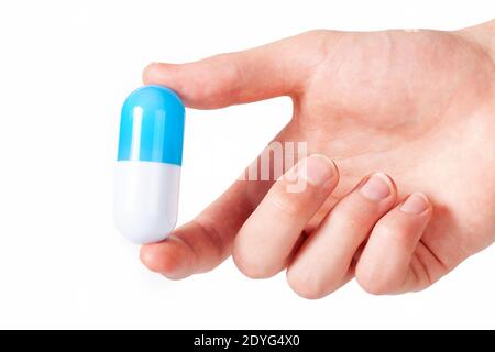 Ärzte Hand hält eine Pille, riesige zweifarbige weiße blaue neue Tablette, Arzt gibt neue Medizin Geste isoliert auf weiß, ausgeschnitten, Rezept Stockfoto