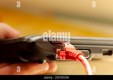 Laptop rotes Netzwerkkabel angeschlossen, Netbook Internet-Anschluss Nahaufnahme, Detail, Kopierplatz. Dünnes Notebook mit RJ45-Stecker, Seitenansicht. Internetzugang Stockfoto