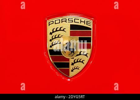 Porsche Auto Markenlogo auf einer glänzend roten Autohaube Nahaufnahme, Makro, Detail, Draufsicht, klassisches Porsche AG Stuttgard Firmenemblem isoliert, Logo von oben Stockfoto