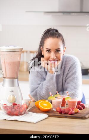 Obst-basierte Ernährung von einer Frau zu Hause durch Mischen von Beeren und Zitrusfrüchten zu einem Smoothie gemacht. Stockfoto