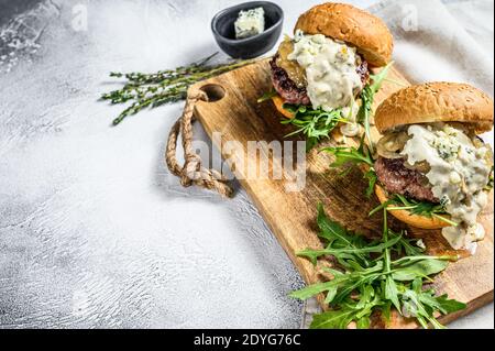 Leckere Burger mit Blauschimmelkäse, marmorierten Rindfleisch, Zwiebelmarmelade und Rucola. Grauer Hintergrund. Draufsicht. Speicherplatz kopieren Stockfoto