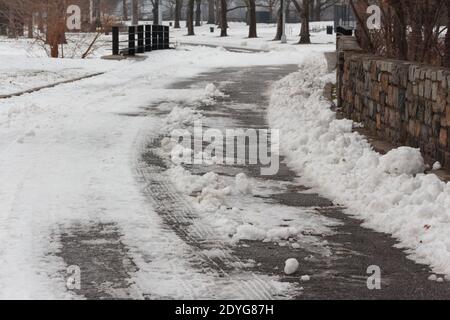 Eine schneebedeckte Straße mit Reifenpanzer im Schnee im Inwood Hill Park, New York Stockfoto