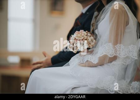 Eine Nahaufnahme einer Braut und eines Bräutigams, die daneben sitzen Einander in der Kirche Stockfoto