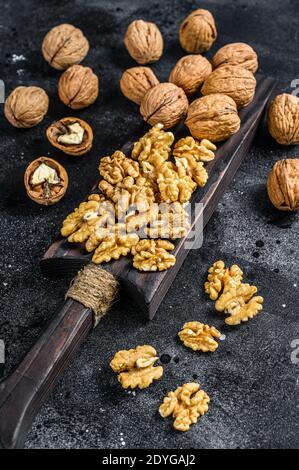 Geschälte Walnüsse Kerne auf Holz Schneidebrett. Schwarzer Hintergrund. Draufsicht Stockfoto