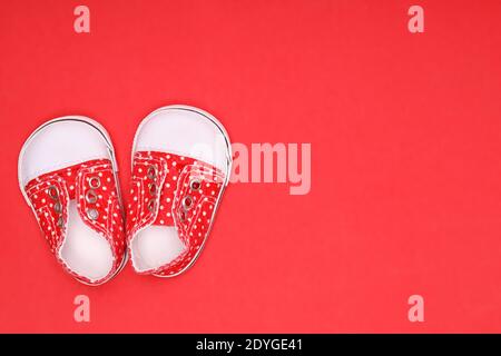 Babyschuhe mit weißen Tupfen auf rotem Hintergrund Stockfoto