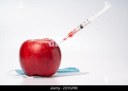 Eine Spritze injiziert einen Apfel, symbolisch für Impfung und medizinische Behandlung Stockfoto