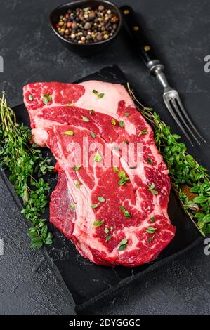 RAW Organic Chuck Eye Roll Fleisch Steak Schnitte. Schwarzer Hintergrund. Draufsicht Stockfoto