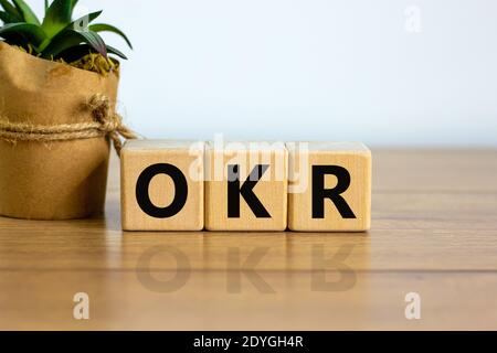OKR-Symbol. Konzeptworte 'OKR - Ziele und Schlüsselergebnisse' auf Kuben auf einem schönen Holztisch, weißer Hintergrund. Hausanlage. Business und OKR - o Stockfoto