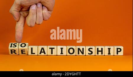 Beziehung oder Isolation. Männliche Hand dreht Würfel und ändert das Wort 'Relationship' in 'Isolationship'. Schöner orangefarbener Hintergrund, Kopierbereich. Stockfoto