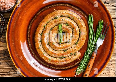 Gegrillte Spiralwurst aus Schweinefleisch und Rindfleisch auf einem rustikalen Teller. Holzhintergrund. Draufsicht Stockfoto