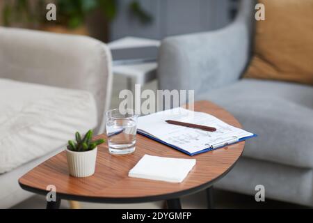 Bild des Tisches mit Dokumenten Pflanze und Glas Wasser Darauf im Zimmer Stockfoto