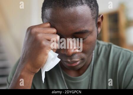 Afrikanischer Mann sitzt verzweifelt mit Serviette in der Hand Stockfoto