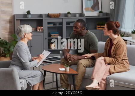 Junges Paar sitzt auf dem Sofa und spricht mit Familie Psychologe Während ihres Besuchs Stockfoto