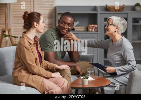 Senior Psychologe im Gespräch mit jungen Paar, während sie auf sitzen Sofa während der Therapie Stockfoto