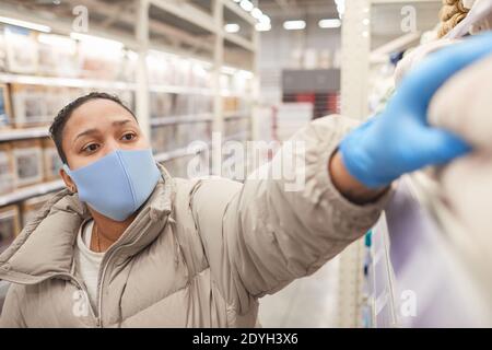 Frau in Maske und in Schutzhandschuhen Einkaufen im Supermarkt Stockfoto