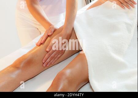 Bein Modellierung Massage, weibliche Masseuse Hände Behandlung junge Frau Oberschenkel auf dem Massagebett im Beauty-Spa-Salon Stockfoto