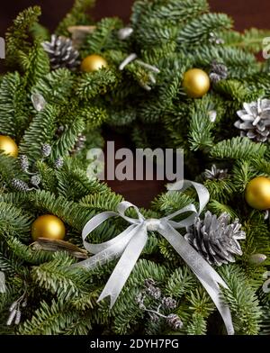 Wunderschön grüner Weihnachtskranz mit goldenen Kugeln auf dunkler Holzfläche, 45 Grad Winkel, satte Farben. Vollansicht Stockfoto