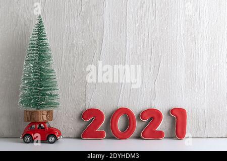 Kleiner Weihnachtsbaum steht auf dem Spielzeugauto neben dem Schild 2021. Speicherplatz kopieren. Stockfoto