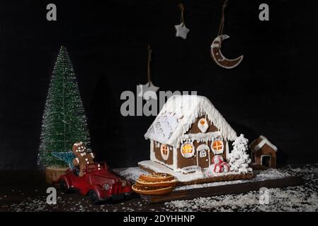 Neue Jahre Zusammensetzung: Lebkuchenhaus, Lebkuchenkekse, Spielzeugauto, künstlicher Weihnachtsbaum Stockfoto