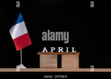 Holzkalender April mit Tisch Französisch Flagge auf schwarzem Hintergrund. Urlaub in Frankreich im April. Stockfoto