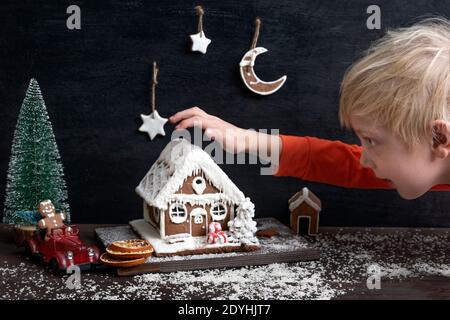 Kind macht Neujahr Komposition aus Lebkuchenhaus, Spielzeugauto und Weihnachtsbaum. Stockfoto