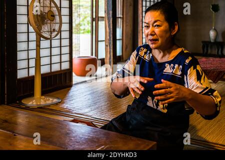 Typisch japanisches Abendessen von Atsuko Kato. Atsuko Kato erklärt die Prinzipien von Kaiseki in ihrem Speisesaal. Es wird ein komplettes Menü mit Zutaten wie Reis und Gemüse serviert, die direkt von lokalen Produzenten stammen. Die Gerichte werden mit Sorgfalt und Kreativität zubereitet, immer inspiriert von den wechselnden Jahreszeiten, und die Präsentation kombiniert visuelle Ästhetik mit authentischen Aromen Stockfoto