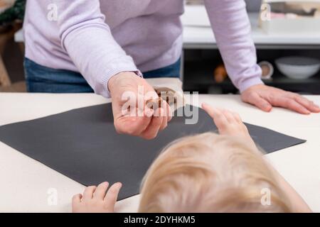 Frau gibt Süßigkeiten an Kind. Kind greift nach dem Süßigkeiten. Stockfoto