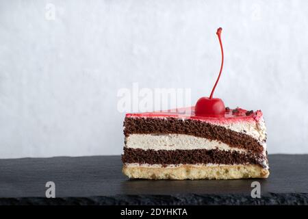 Stück Schoko-Kuchen mit Kirschen garniert. Seitenansicht zum Stück Kuchen auf weißem Hintergrund. Stockfoto