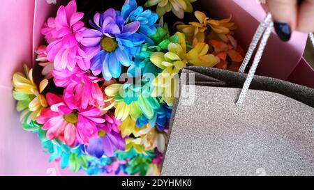 Dekorative Komposition - Frau hält bunte Regenbogen Bouquet in rosa Verpackung und Geschenk in Silber-Paket Stockfoto