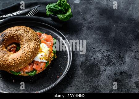 Geräucherter Lachs Bagel Toasts mit Weichkäse, Spinat und Ei. Schwarzer Hintergrund. Draufsicht. Speicherplatz kopieren Stockfoto