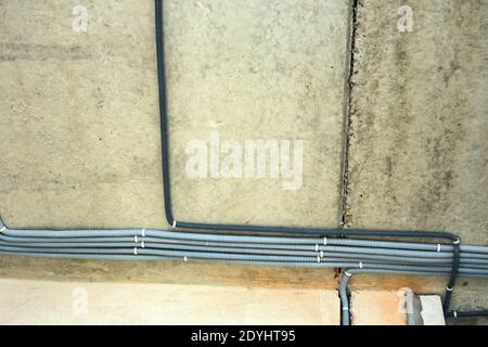 Elektrokabel in einer Schutzwellung an der Decke und an der Wand in einem Raum, in dem Bauarbeiten durchgeführt werden. Stockfoto