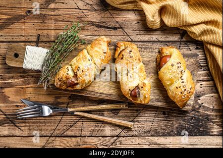 Hausgemachte Pretzel eingewickelt Hot Dog, Wurst im Teig. Holzhintergrund. Draufsicht Stockfoto