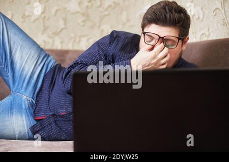 Konzept, ein kaukasischer Mann mit Brille verletzt seine Augen hinter einer Notiz Buche, Kopien des Raumes Stockfoto
