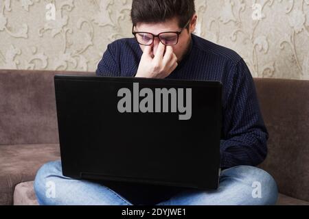 Konzept, ein kaukasischer Mann mit Brille verletzt seine Augen hinter einer Notiz Buche, Kopien des Raumes Stockfoto