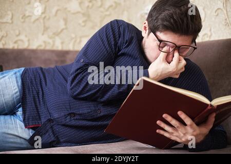 Konzept, kaukasischen Mann trägt Brille hat Wunde Augen beim Lesen eines Buches, Kopien des Raumes Stockfoto