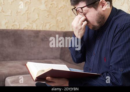 Konzept, kaukasischen Mann trägt Brille hat Wunde Augen beim Lesen eines Buches, Kopien des Raumes Stockfoto