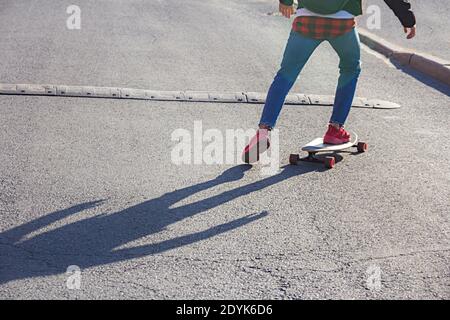 Ansicht der Beine eines jungen Skateboarders Reiten auf einem Skateboard nähert sich der Geschwindigkeit Bump auf einer Stadtstraße Stockfoto