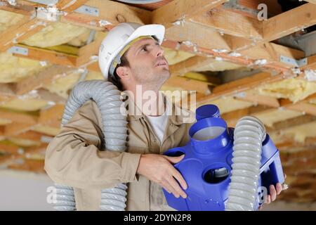 Männlicher Baumeister, der eine Klimaanlage installiert Stockfoto