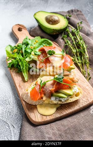 Gesundes Sandwich mit Avocado und Lachs. Spinat und Rucola Salat. Weißer Hintergrund. Draufsicht Stockfoto