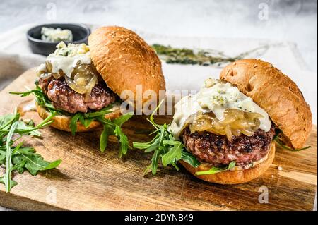 Leckere Burger mit Blauschimmelkäse, marmorierten Rindfleisch, Zwiebelmarmelade und Rucola. Grauer Hintergrund. Draufsicht Stockfoto