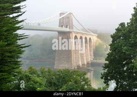 Die Menai Suspension Bridge, die im frühen Morgennebel nach Anglesey übergeht. Stockfoto