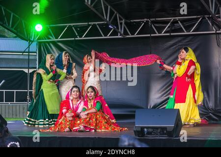Eine Gruppe von indischen Frauen in bunten Saris Durchführung einer Schal Tanz auf der Bühne während Diwali Festival Feiern Stockfoto