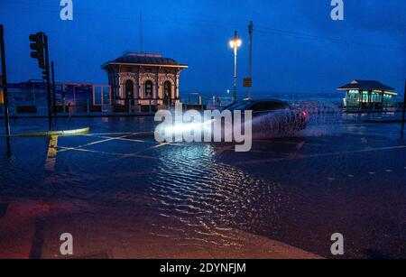 Brighton UK 27. Dezember 2020 - EIN Auto fährt am frühen Morgen durch Überschwemmungen an der Strandpromenade von Brighton, als Sturm Bella Großbritannien heute mit starken Winden und starken Regenfällen schlägt, die Überschwemmungen und Schäden in einigen Gebieten verursachen : Credit Simon Dack / Alamy Live News Stockfoto