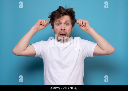 Wütend Mann mit shaggy Frisur mit unzufriedenen Blick. Misstrauen, Skepsis und Zweifel. Stockfoto