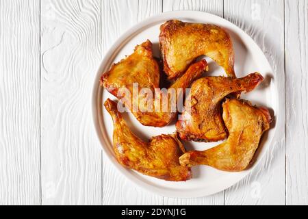 Knochen-in gerösteten Hähnchenbeine auf einer weißen Platte auf Holztisch serviert, horizontale Ansicht von oben, flach liegend, Freiraum Stockfoto